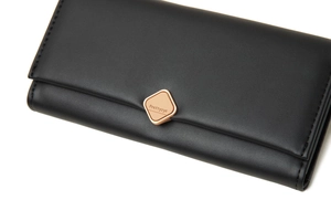 Gros plan du fermoir en métal doré sur le portefeuille long en cuir synthétique noir