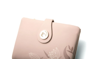 Gros plan détaillé sur la boucle métallique dorée du portefeuille en cuir texturé rose