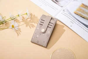 Close-up of khaki floral print card holder with golden snap and lychee grain leather