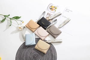 Flat lay of multiple colorful PU leather short tri-fold wallets with elegant wristlets