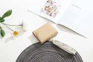 Detail view of beige leather wallet with floral strap and gold logo on woven mat