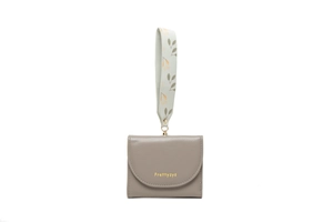 Close-up of light grey bifold leather wallet with gold logo and floral pattern strap