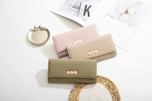 Detailed view of pink, beige and olive green PU leather long wallets with leaf-motif metal hardware