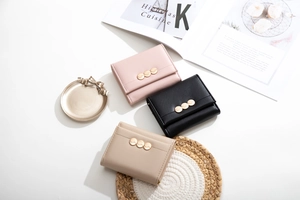 Short tri-fold wallets in pink, black, and beige with triple gold circular buckles