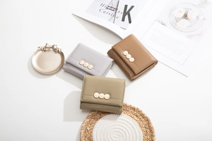Three-fold leather wallets in grey, brown, and green with leaf-shaped buckles on a clean background