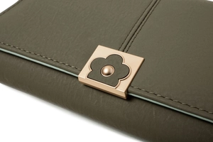 Détail du portefeuille en cuir vert avec fermoir fleur or rose et couture précise