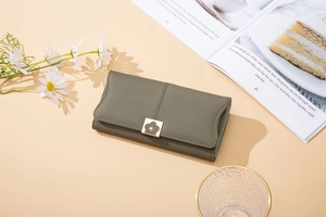 Détail d'un portefeuille long en cuir mat vert-gris avec boucle fleurie dorée