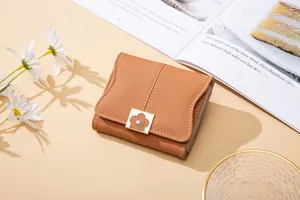 Detail of caramel brown PU leather wallet with lychee texture and floral clasp accent