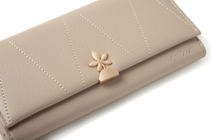 Detail of taupe leather wallet featuring V-shaped stitching and gold flower clasp