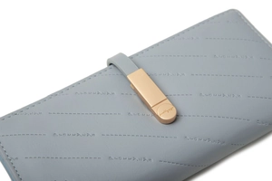 Detail of light blue-grey leather wallet showing diagonal stitching and gold buckle