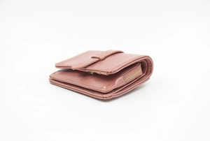 Side view of dusky pink short wallet with matte leather and metal zipper detail
