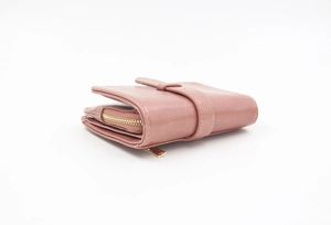 Detail view of dusty pink leather wallet with gold zipper and snap closure strap