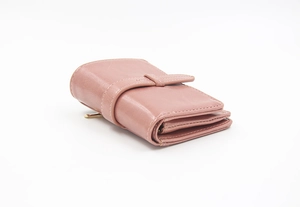 Detail of vintage oil wax leather wallet with retro strap buckle in soft lotus pink