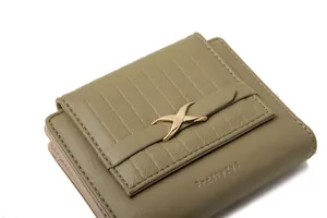 Close-up of olive green tri-fold faux leather wallet with quilted pattern and gold bow