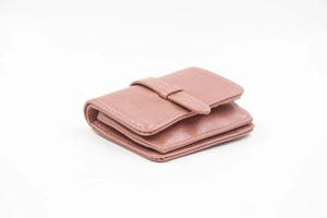 Close-up of pink trifold leather wallet showing internal storage slots and fine stitching