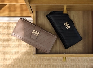 Close-up of quilted leather wallets with gold buckles in khaki and black colors