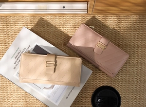 Detailed view of quilted faux leather long wallets with striped fold-over buckle closures