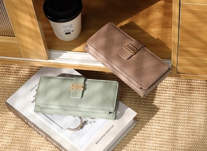 Close-up of quilted PU leather long wallets with metallic buckle closure and accordion folds