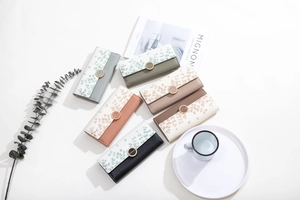 Flat lay of multiple PU leather trifold wallets with elegant leaf prints and ring buckles