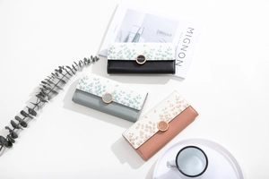 Detailed flat lay of three trifold long wallets with leaf print and round metal buckles