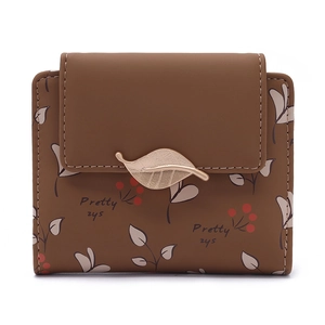 Vue détaillée du portefeuille en cuir marron avec motifs feuilles et fermoir doré