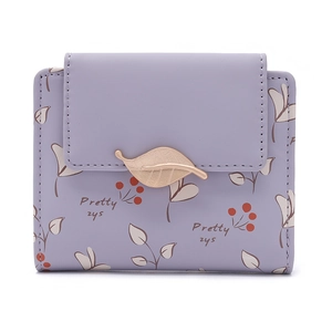 Détail d'un petit portefeuille violet avec fermoir feuille dorée et motif floral de baies