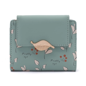 Détail du petit portefeuille vert avec fermoir feuille dorée et motifs botaniques