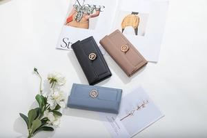 Detailed view of three long tri-fold wallets in black, pink and blue with leaf buckle