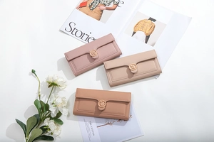 Detailed view of three tri-fold long wallets in pink, beige, and brown with leaf buckle