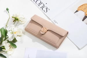 Detail of leaf buckle closure and stitching on a beige tri-fold faux leather long wallet