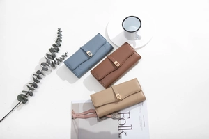 Three leather wallets in grey-blue, tan, and beige colors with gold D-buckle detail