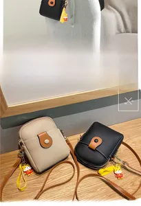 Detail view of mini crossbody phone bags in litchi PU leather with cute tiger charm