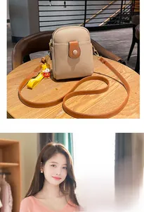 Detail of beige litchi grain phone bag with contrast flap and cute tiger charm