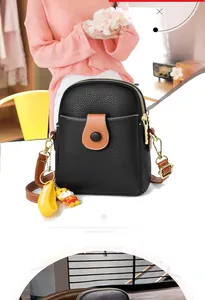 Detail of black lychee grain mini crossbody bag with cute yellow tiger plush toy charm