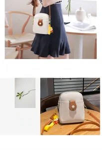 Detail of a creamy white vertical mini crossbody bag with litchi texture and tiger pendant
