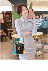 Detail of black lychee grain PU phone bag with brown strap and cute yellow charm