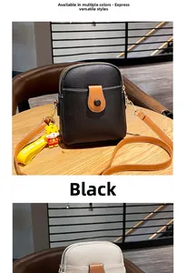 Detailed view of black litchi pattern leather phone bag with brown strap and tiger charm