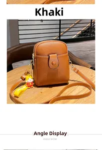 Detailed view of khaki pebbled leather phone bag with dual zippers and cute tiger charm
