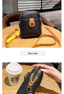 Side view detail of black litchi pattern phone bag with brown strap and tiger charm