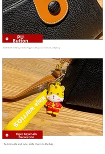 Detail of PU button closure and tiger charm on black lychee grain crossbody bag