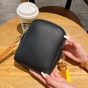 Detail of black litchi grain phone bag with double zippers and brown leather strap