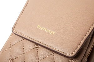 Macro shot of quilted beige PU leather detail and embossed logo on mini shoulder bag