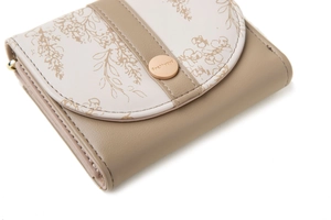 Close-up of short trifold wallet featuring floral print and gold metal clasp closure