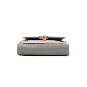 Detail of grey-green litchi texture leather wallet with pink flap and heart pendant