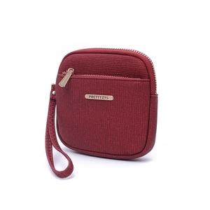 Detail of deep red textured leather wristlet wallet with gold brand logo and zipper