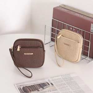 Detail view of two textured zip wallets in dark brown and light gold with wrist straps