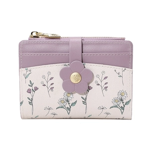 Detail view of floral flap buckle and gold leaf zipper on a leather card holder