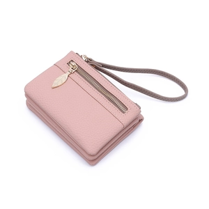 Detail of pink pebbled leather wallet featuring a golden leaf zipper pull and wrist strap