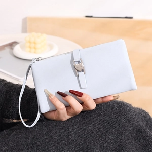 Close-up of light blue leather clutch with heart charm, wristlet strap, and buckle detail