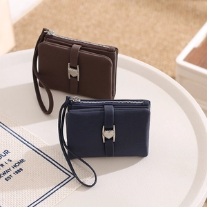 Detail of cross-grain PU leather wallets in brown and blue with heart-shaped metal buckles